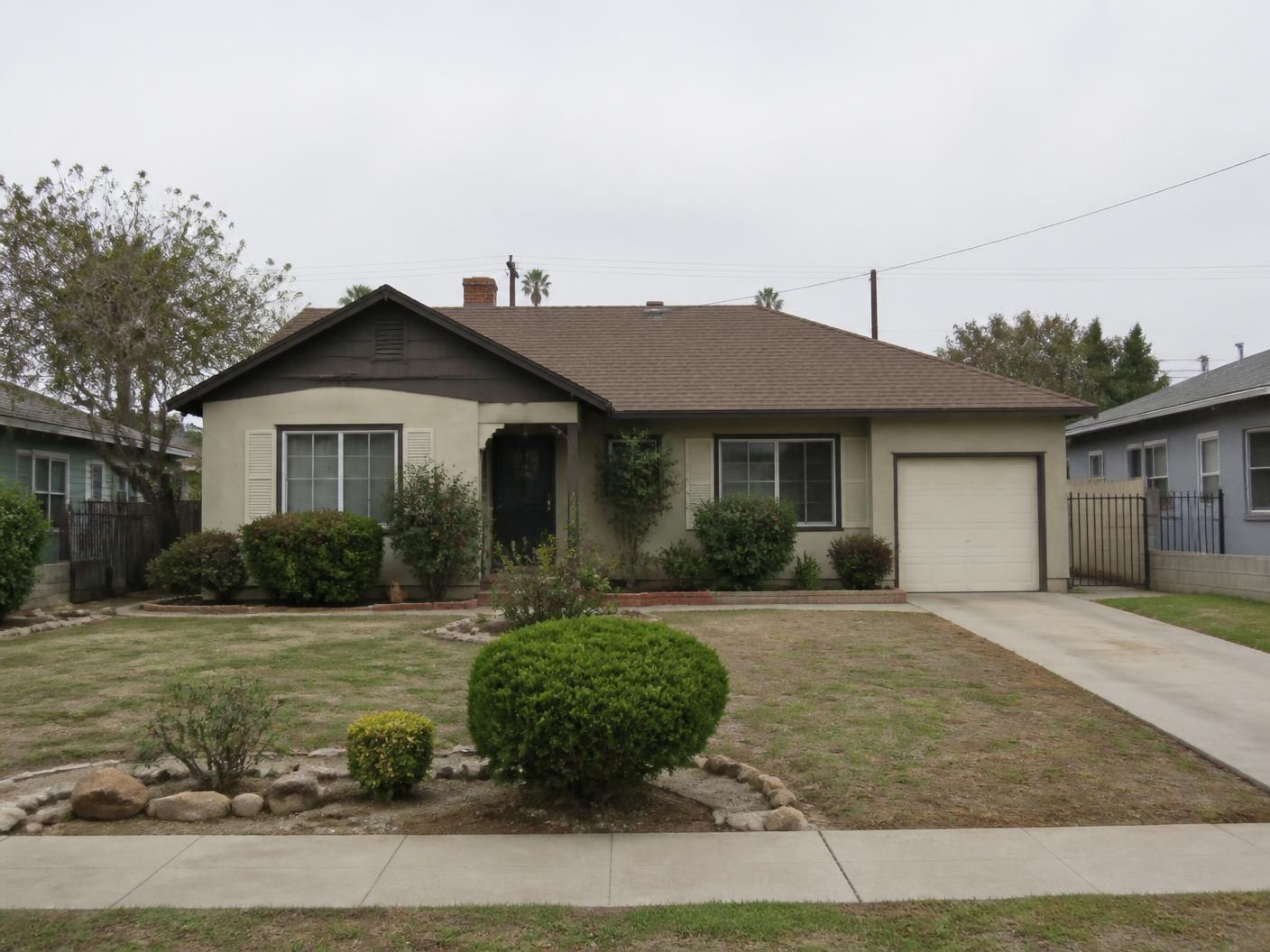 An older Southern California house with dated paint and a worn front yard